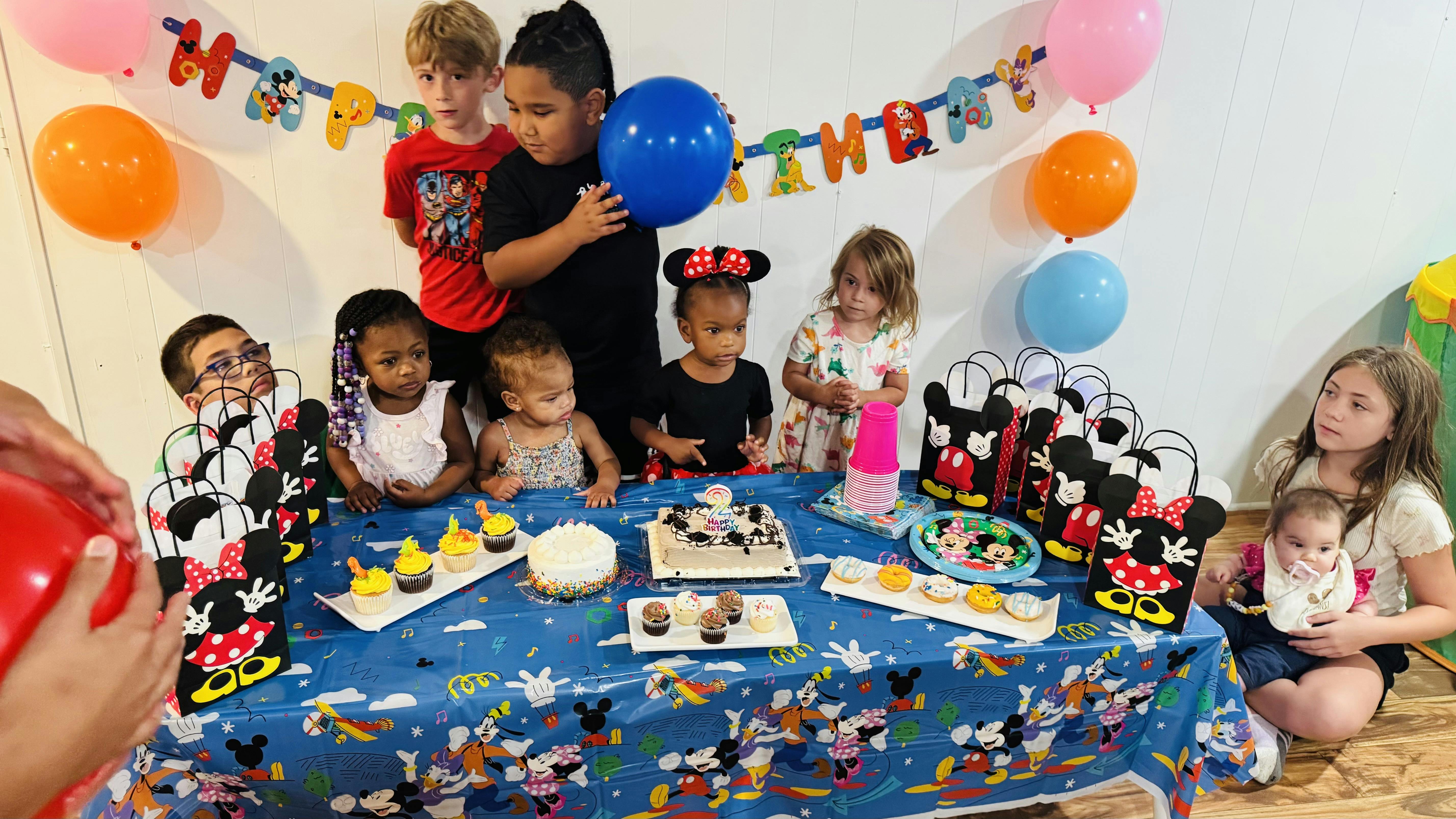 Children celebrating a birthday party with cake, cupcakes, and balloons
