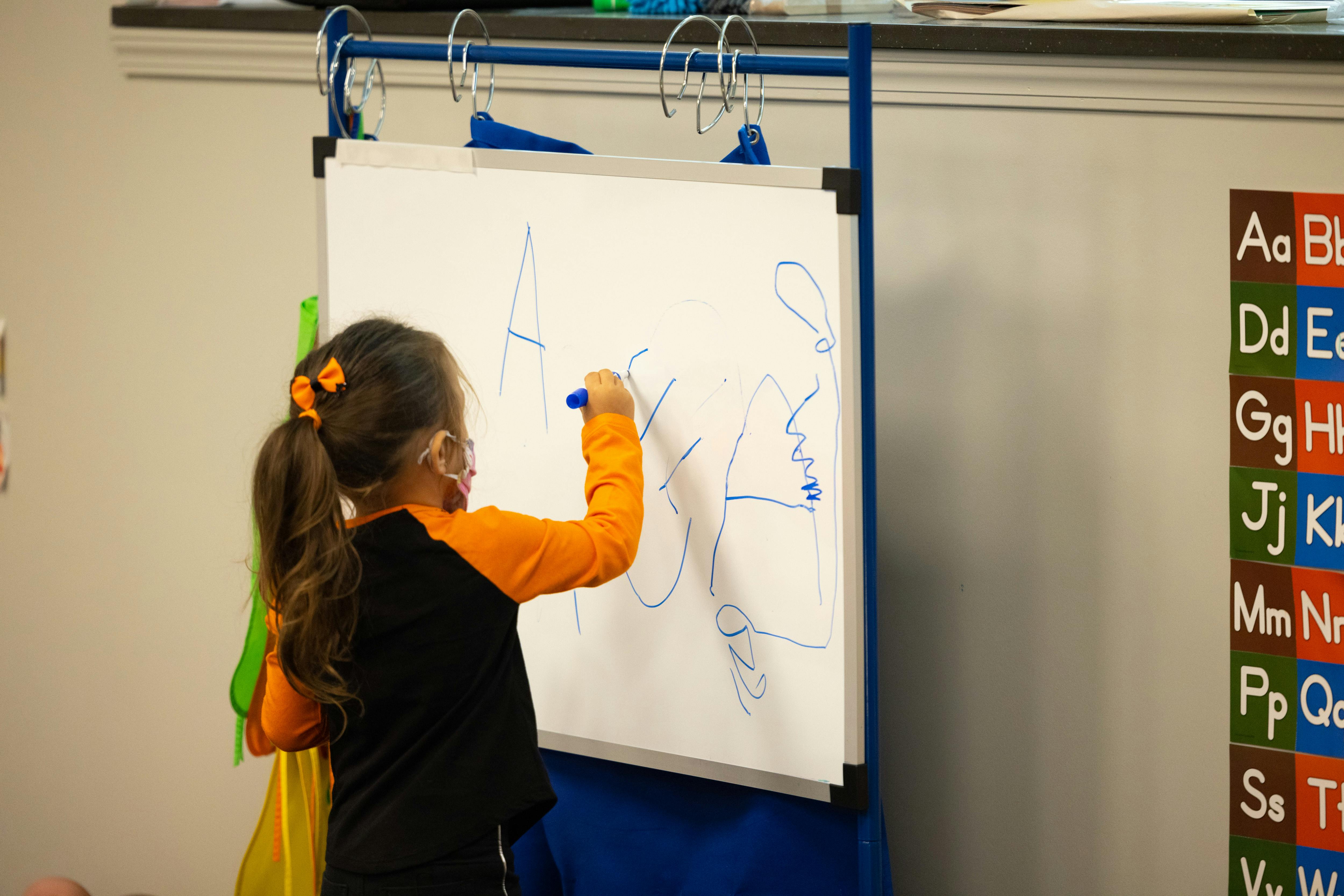 Child drawing on a whiteboard in a classroom