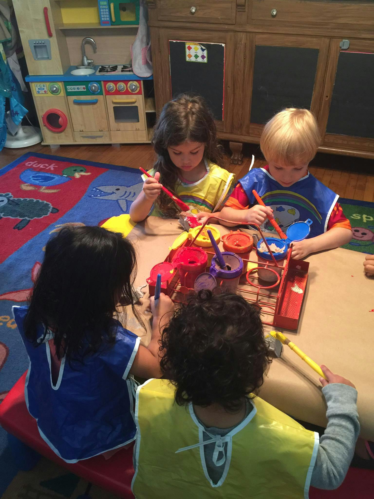 Four children painting at a table