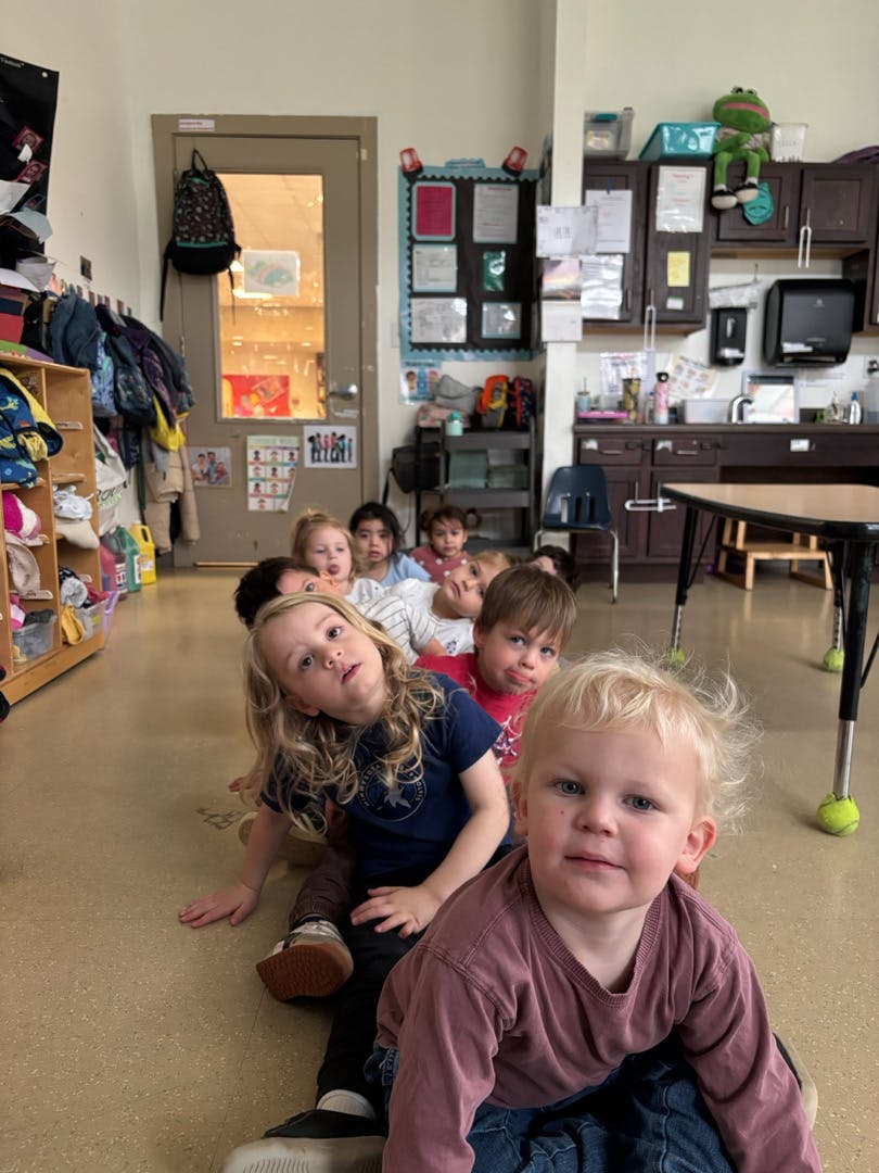 Children sitting in a line on the floor in a classroom