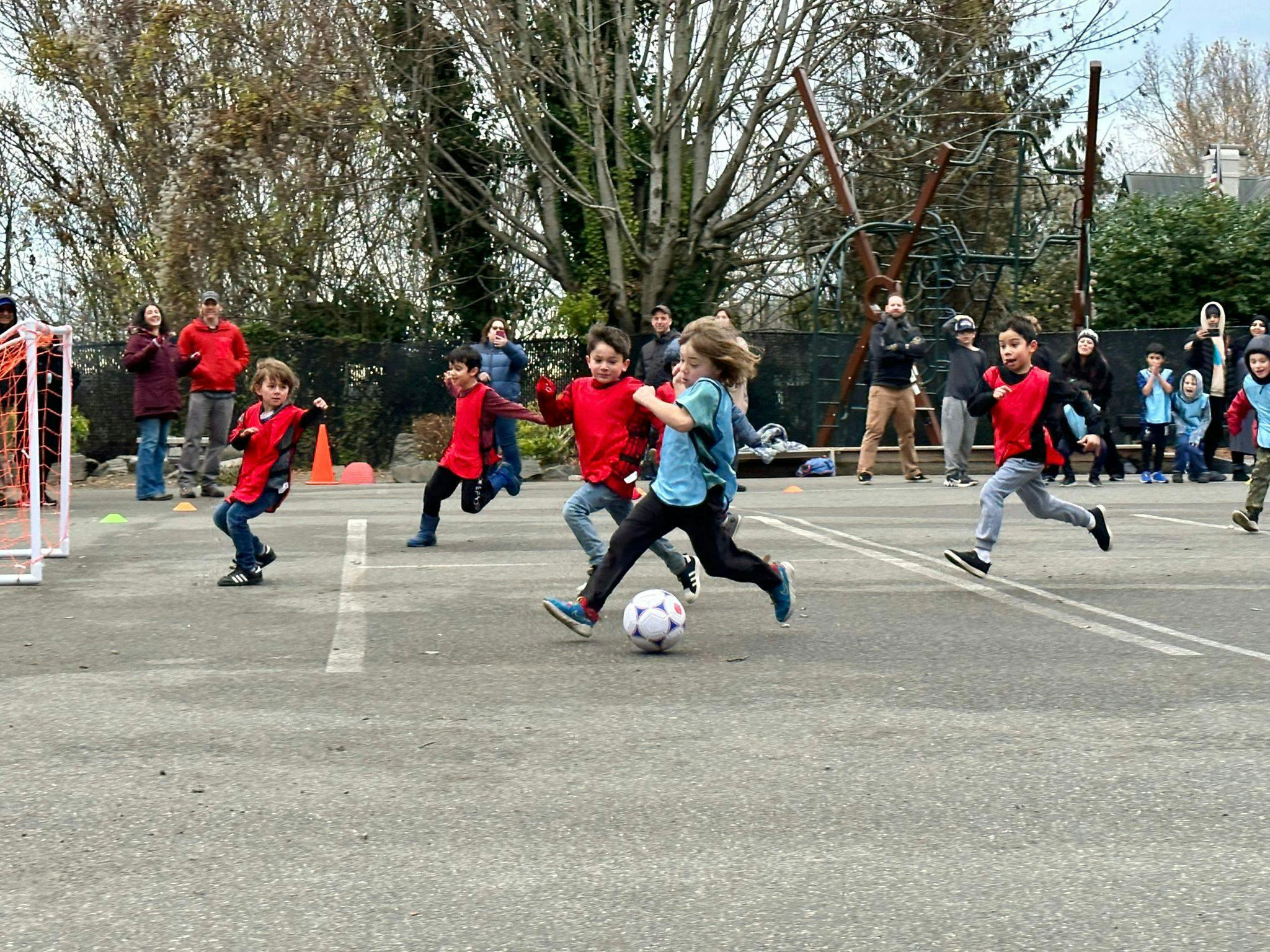 Children playing soccer on an asphalt court