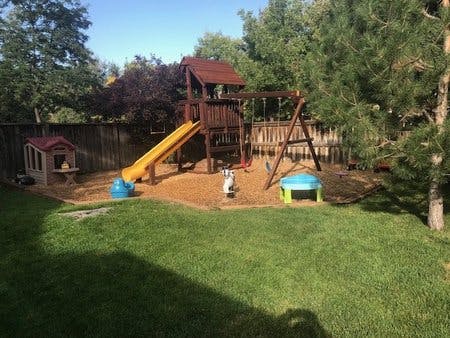 Wooden playset with slide and swings in a backyard