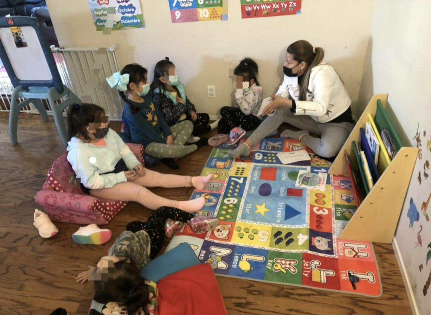 Adult and children sitting on floor with colorful rug in classroom