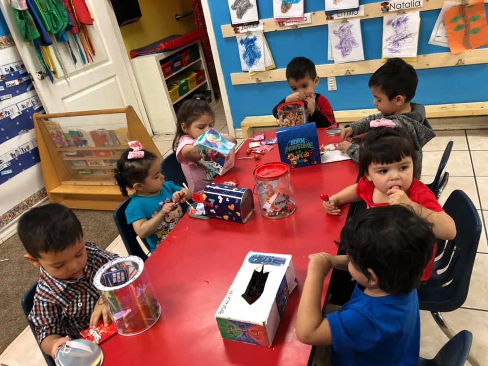 Children sitting at a red table with craft supplies
