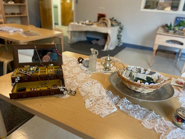 Open jewelry box with necklaces and rings on a table with lace runner