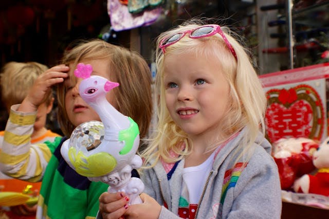 Child holding a toy bird, another child in the background