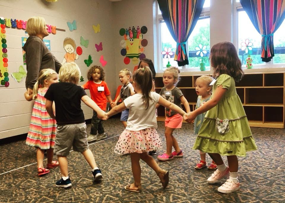 Adult and children holding hands in a circle in a classroom