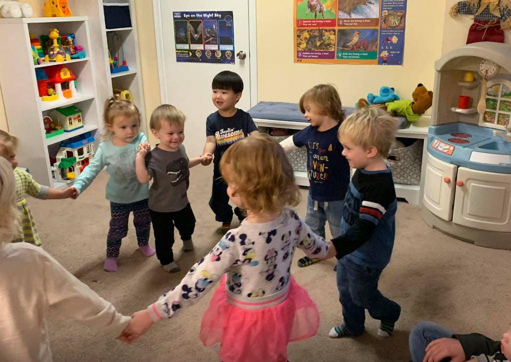 Children holding hands in a circle in a classroom