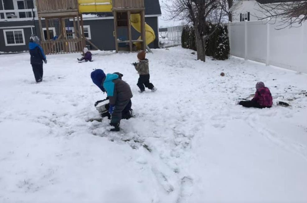 Children playing in the snow in a backyard