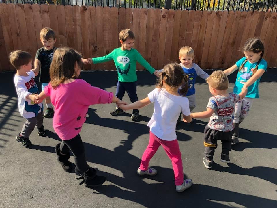 Group of children holding hands in a circle outdoors
