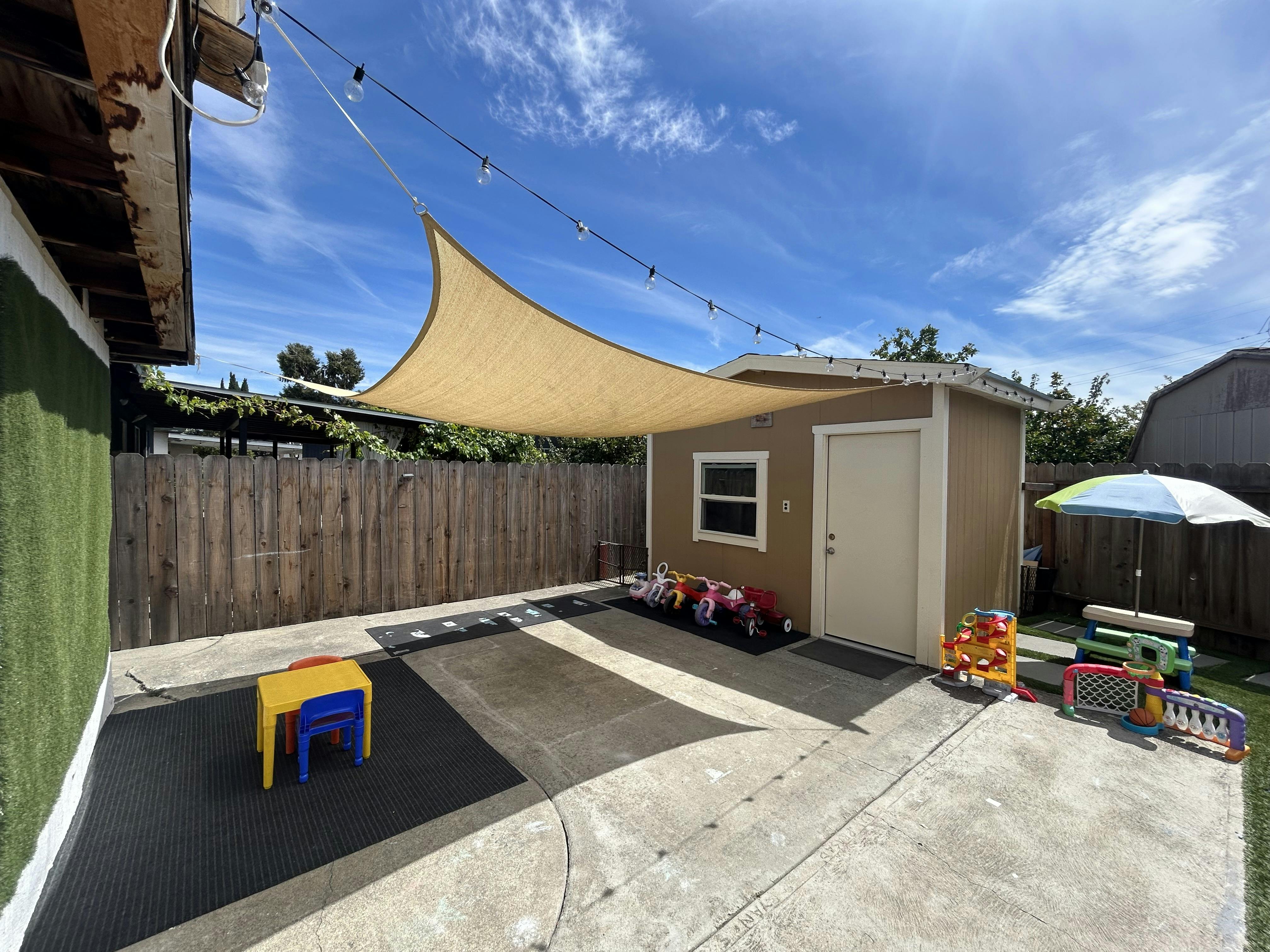 Play area with children toys and shade sail in a backyard