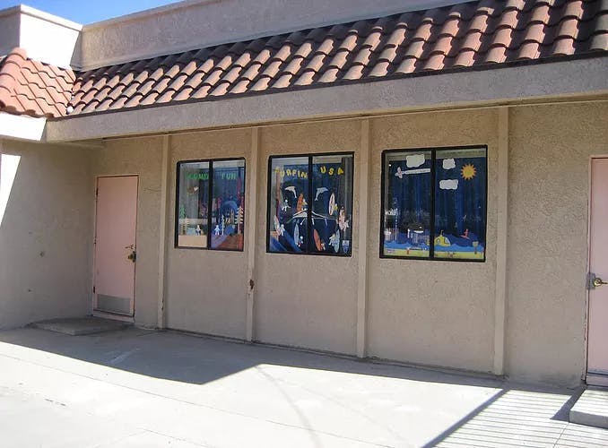 Exterior of a building with three windows displaying children's artwork