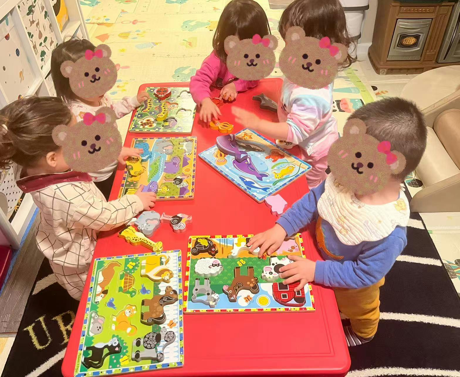 Five young children playing with puzzles around a red table