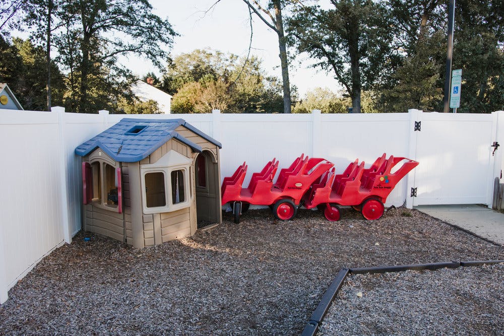 Playhouse and red ride-on toy train in a fenced yard