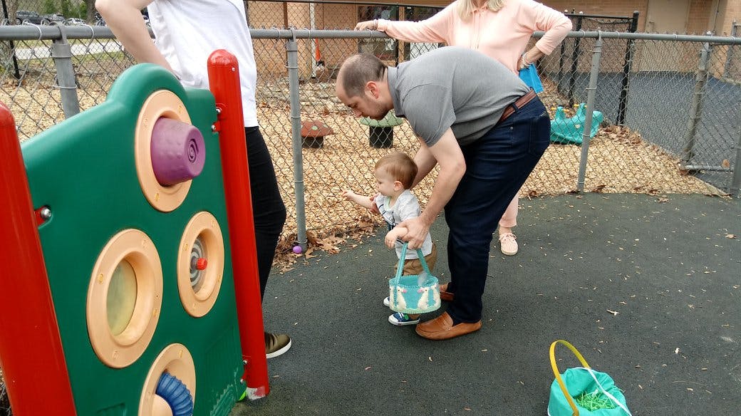 Adult helping a child with a basket on a playground