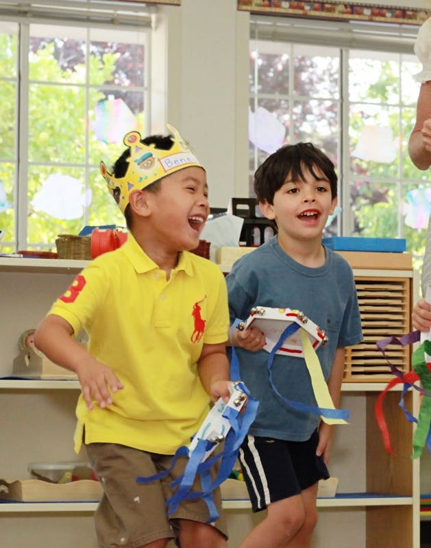 Two children holding crafts and laughing