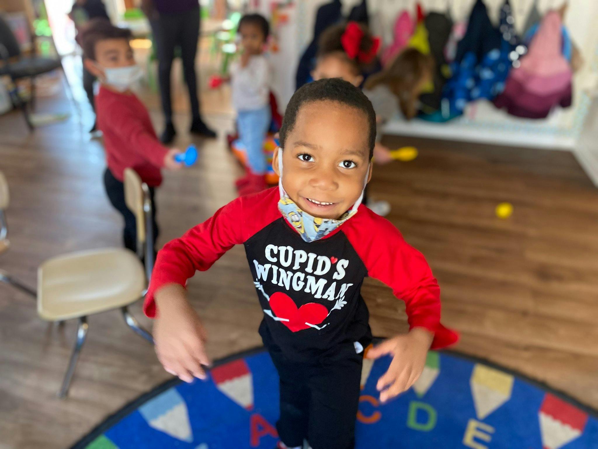 Child wearing a mask and a shirt that says "Cupid's Wingman"