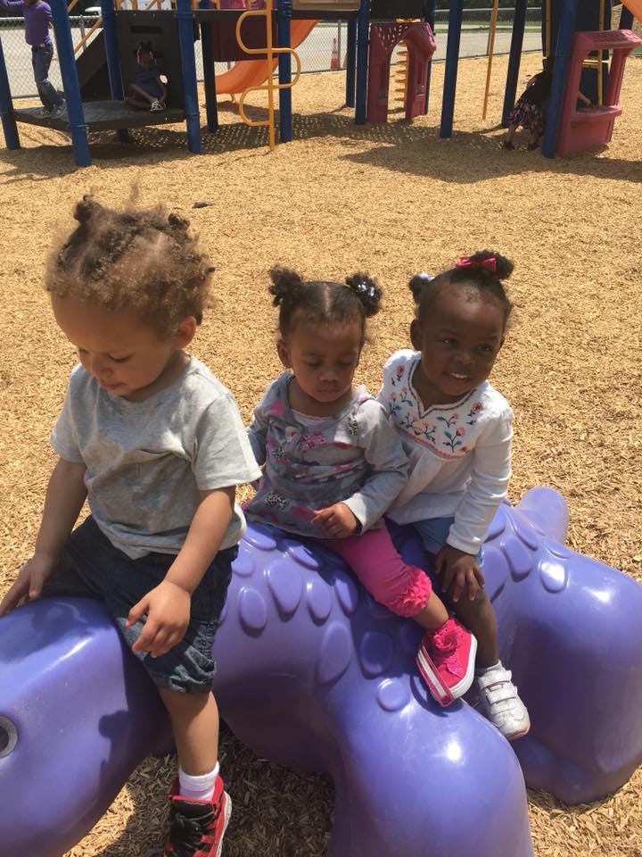 Three children on a purple spring rider at a playground