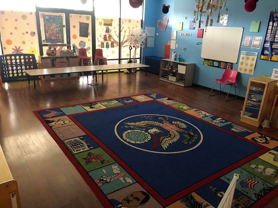Classroom with a large blue rug, tables, and chairs