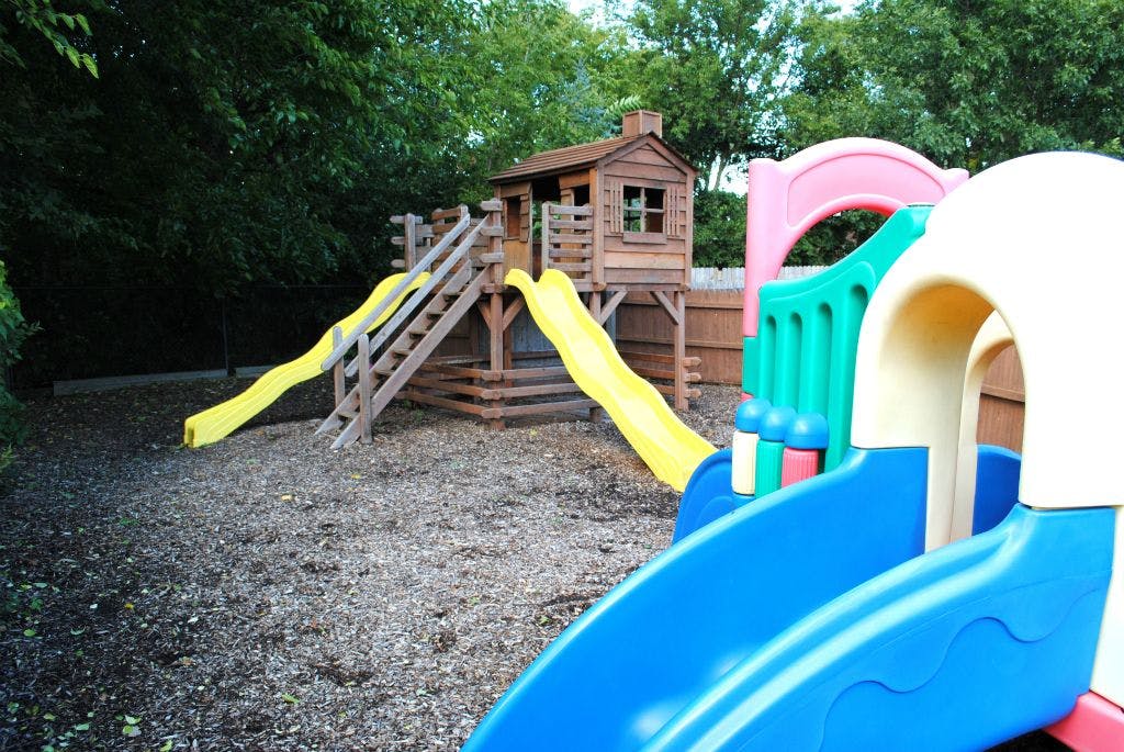 Playground with wooden playhouse and multiple slides