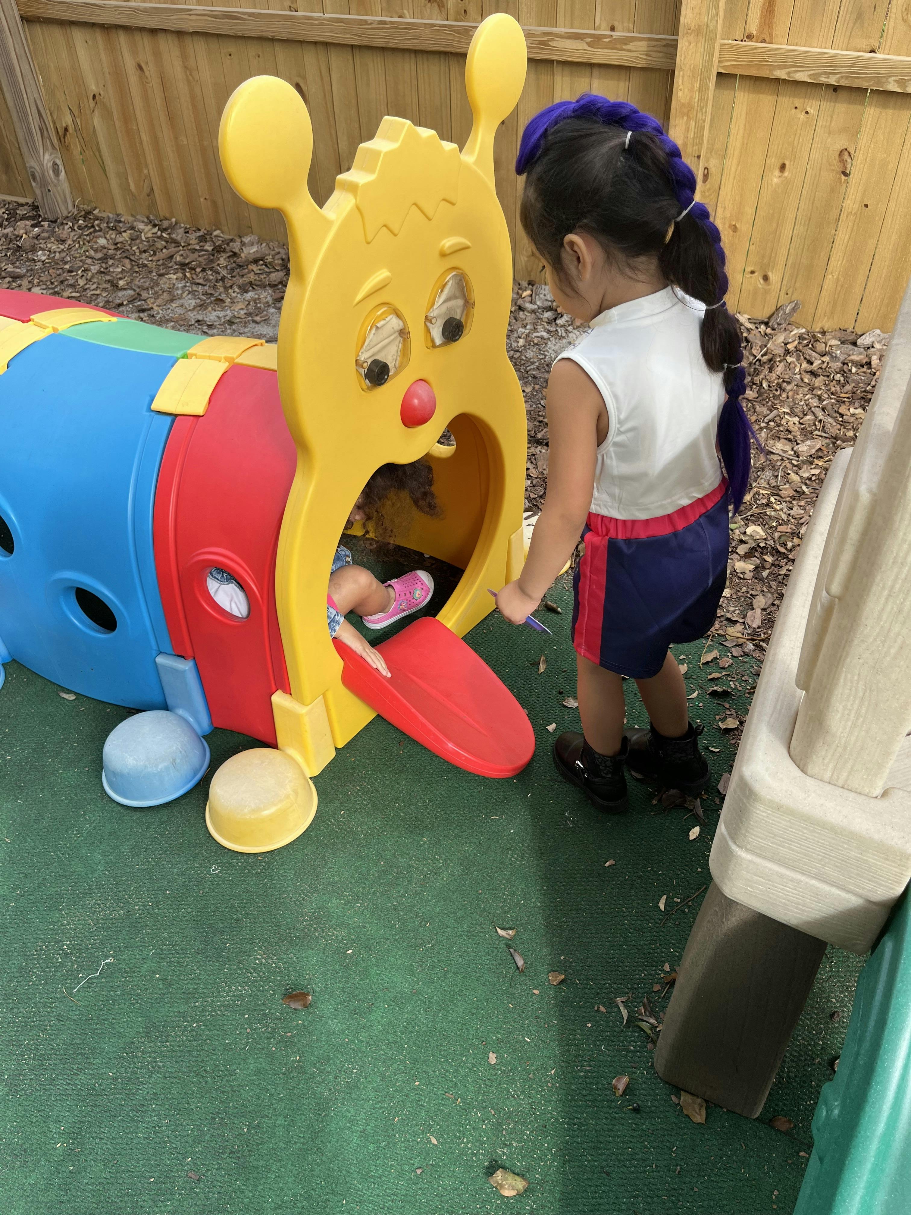 Child looking at another child in a caterpillar play tunnel