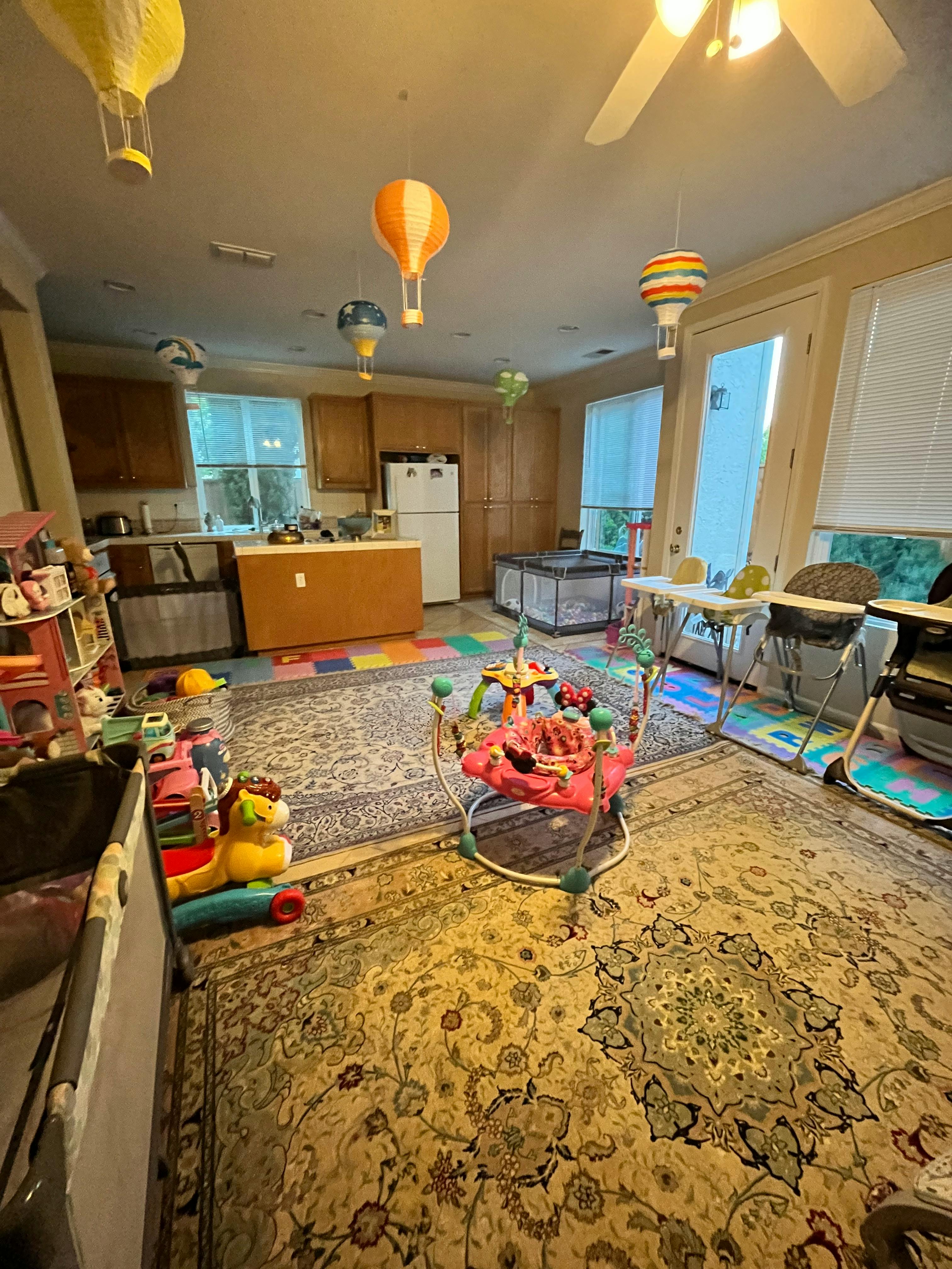A room with a kitchen, baby play area, and hot air balloon decorations