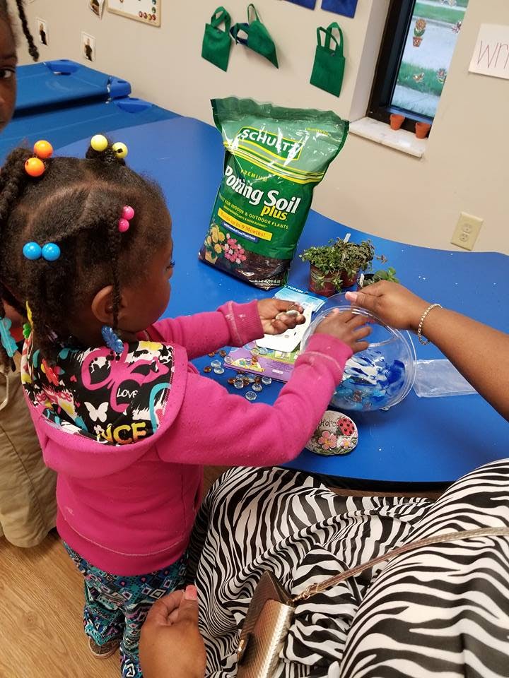 Child and adult hands working with planting materials on a blue table