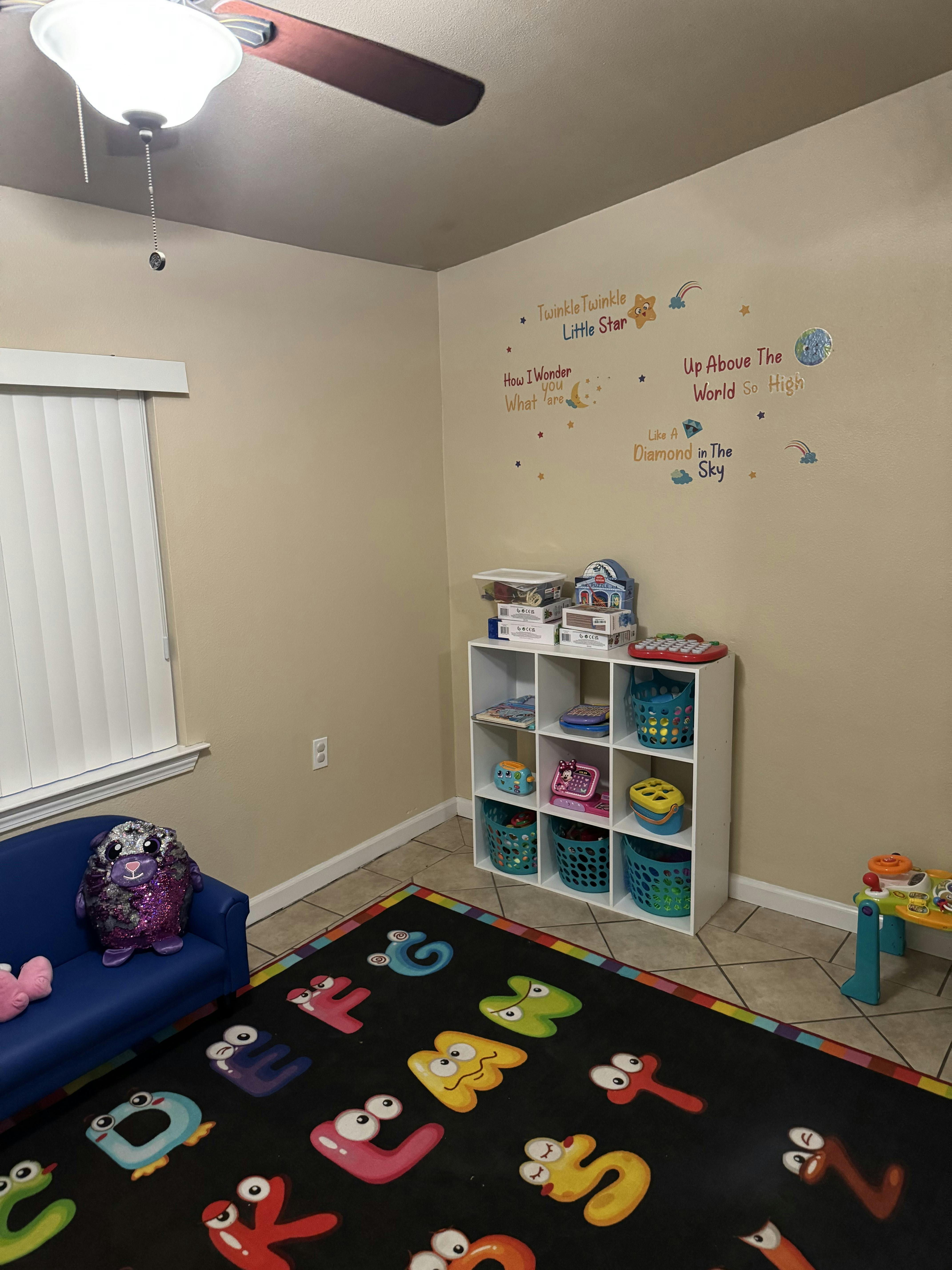 Playroom with alphabet rug, blue couch, and storage shelves