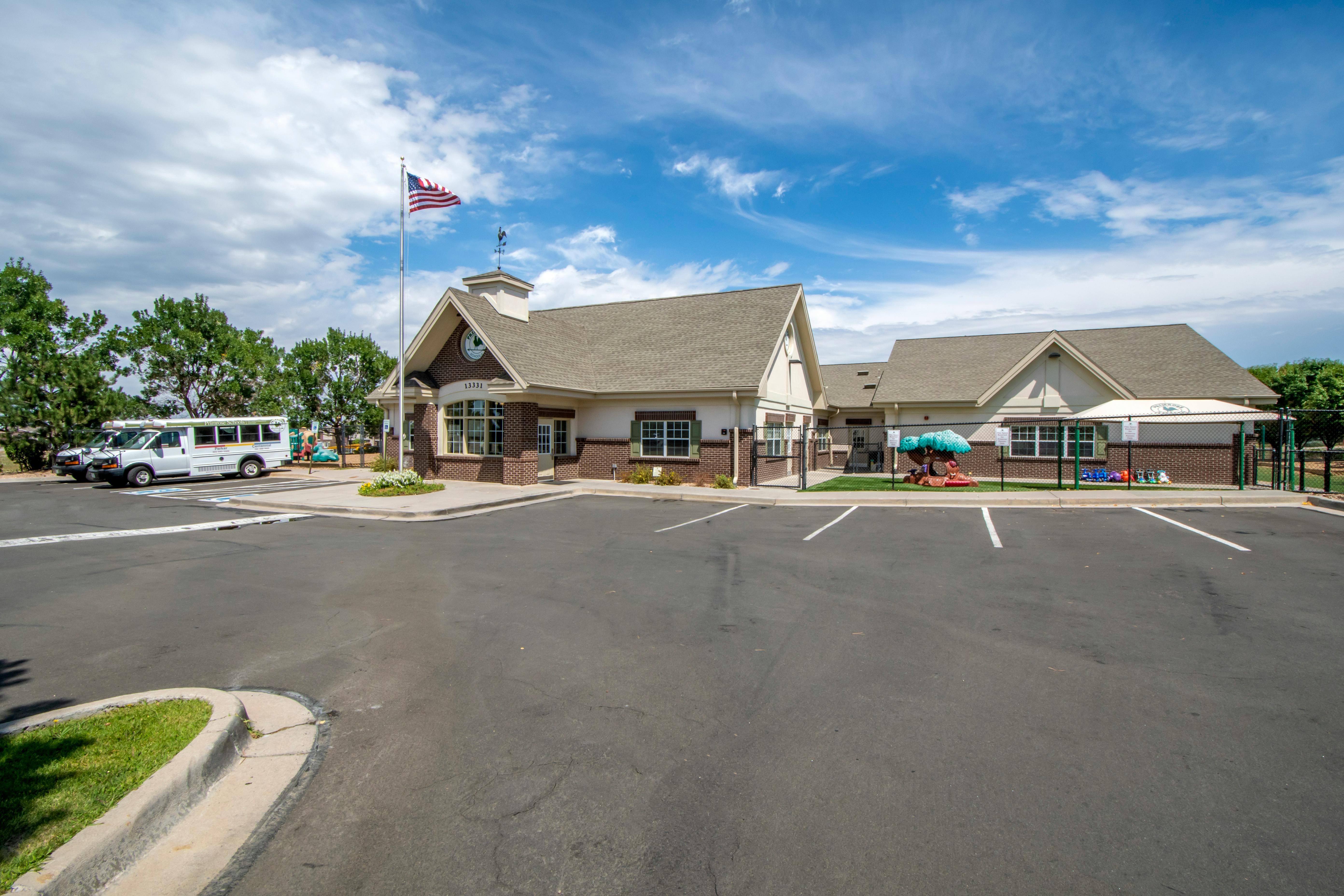 A low-rise brick building with a pointed roof and an American flag flying on a pole