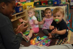 Adult interacting with three babies in a play area