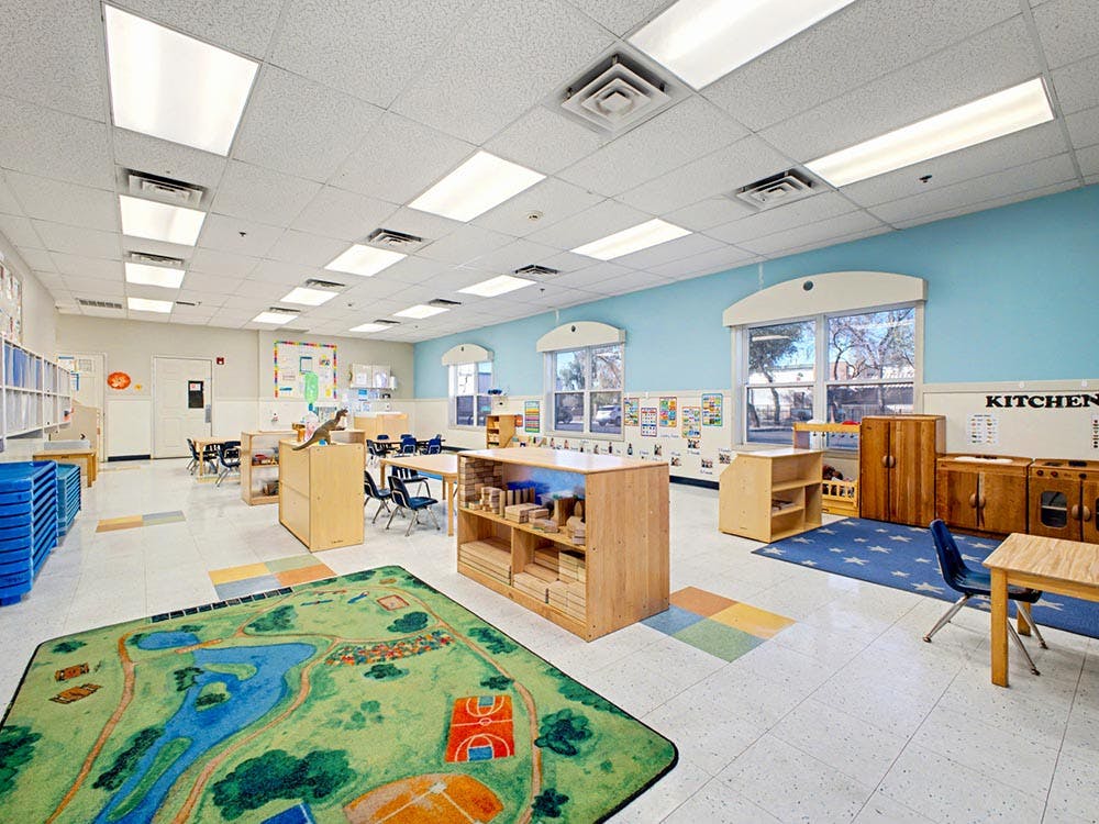 Empty classroom with children's furniture and a play rug