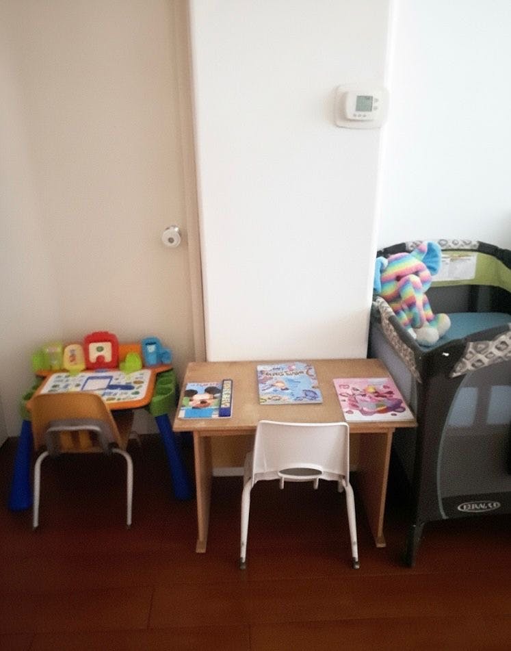 Two small tables with chairs next to a playpen