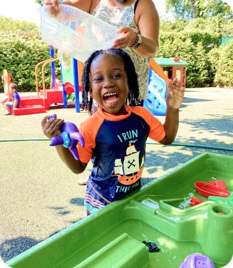 Child in a rash guard getting water poured on their head
