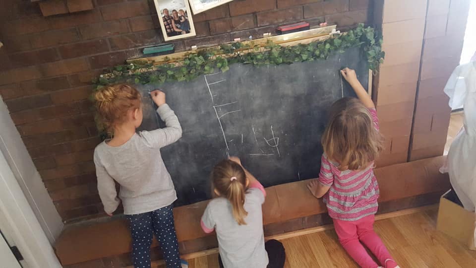 Three children drawing on a chalkboard