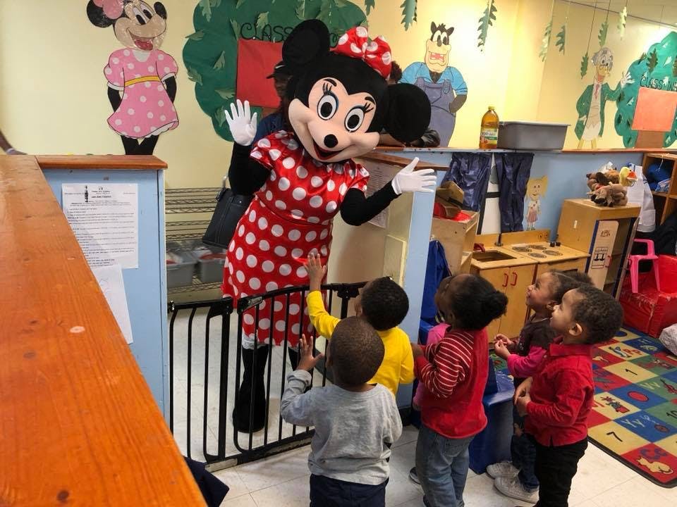 Person in Minnie Mouse costume interacting with children in a classroom