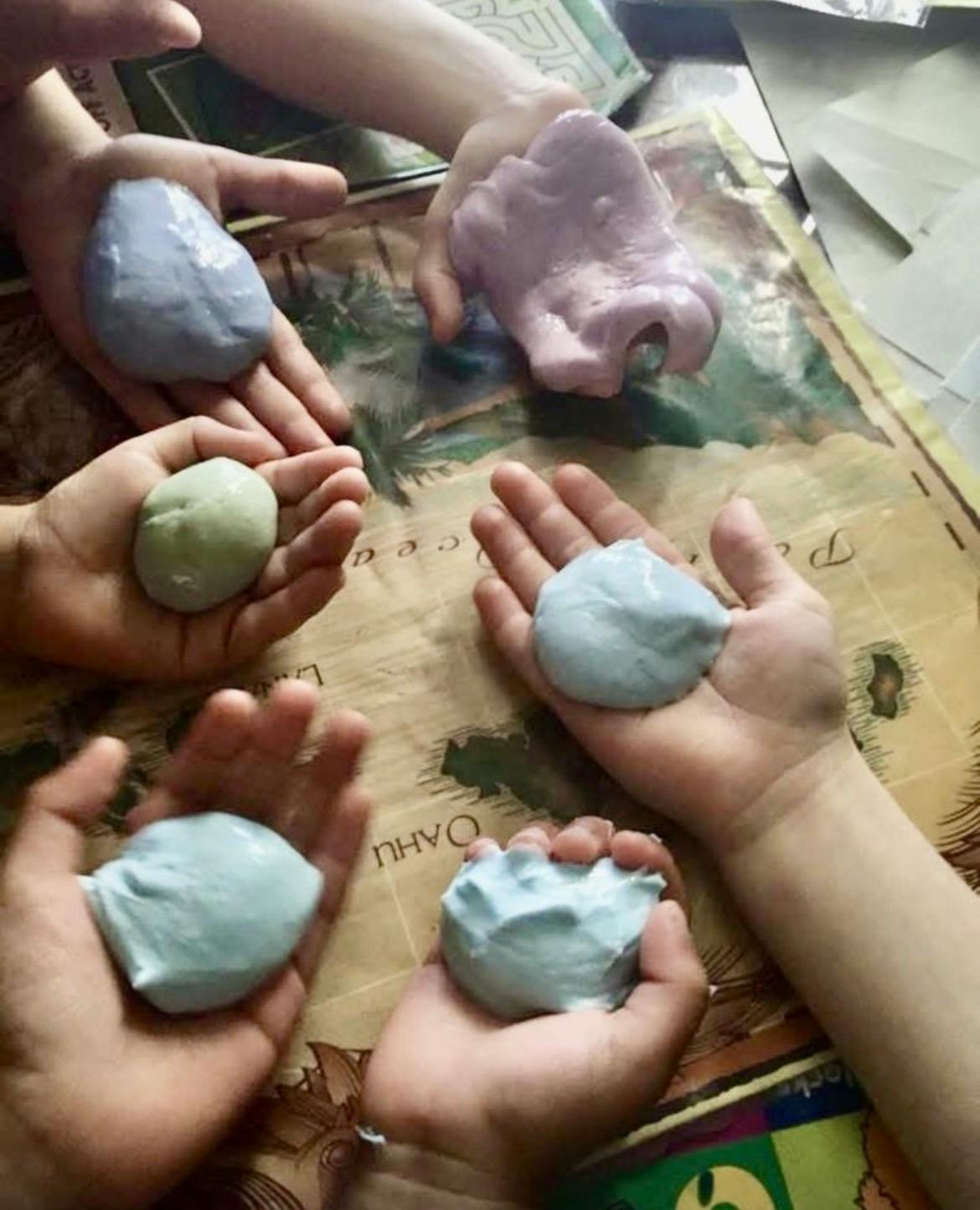 People holding various colors of slime in their palms