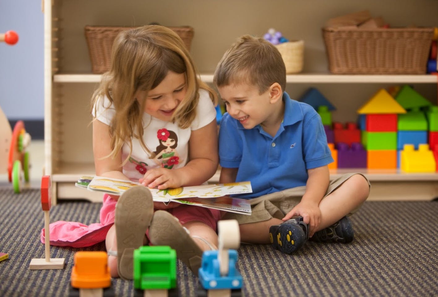 Two children sitting on the floor reading a book together