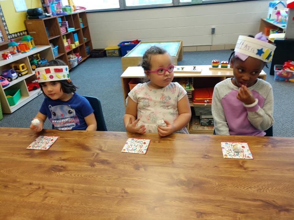 Three children sitting at a table in a classroom