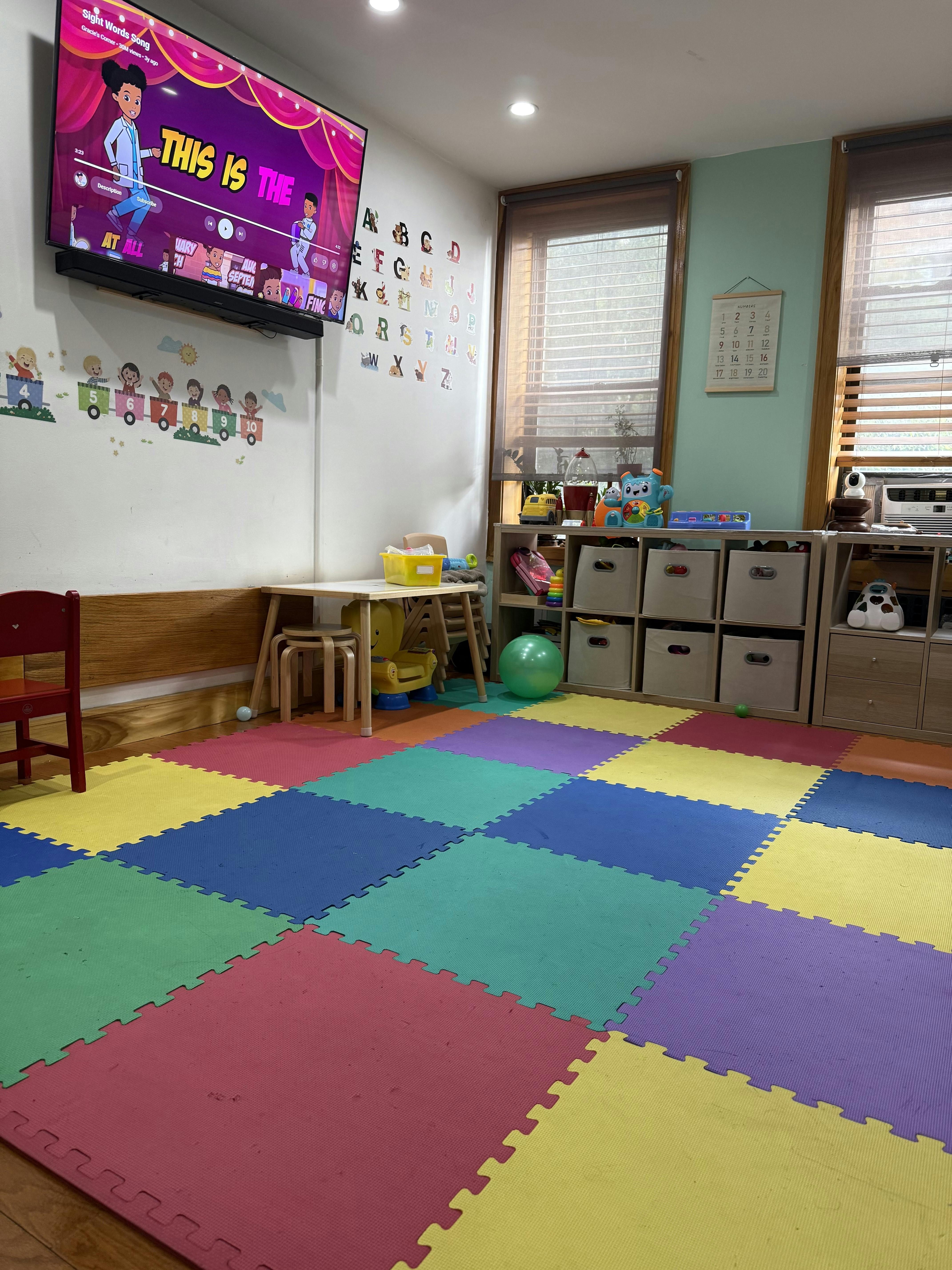 Playroom with colorful foam floor tiles, a TV, and storage shelves