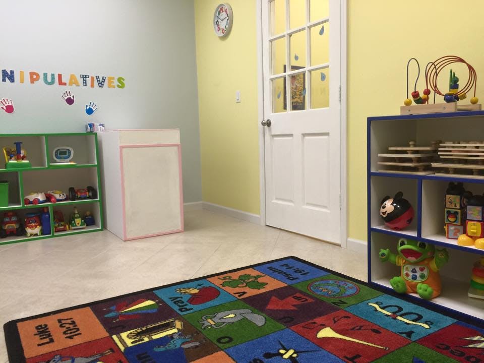 Playroom with colorful rug, shelves of toys, and a door