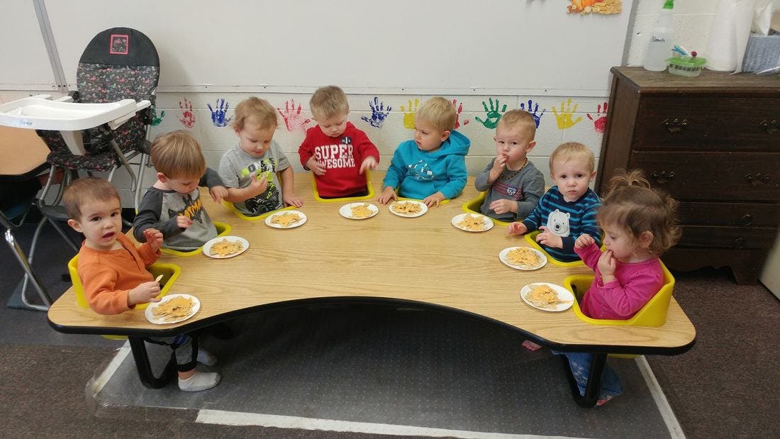 Multiple children sitting at a table with plates of food