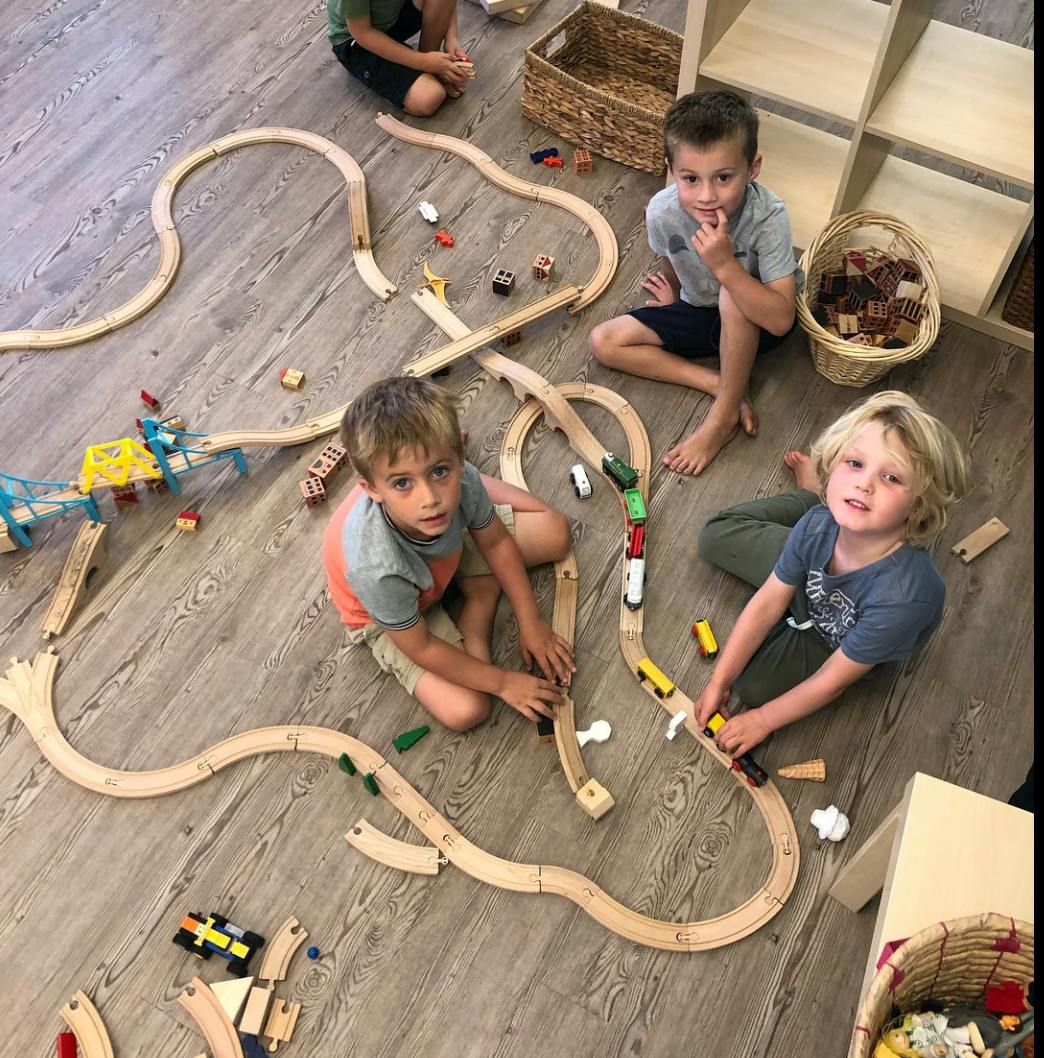 Children playing with a wooden train set on the floor