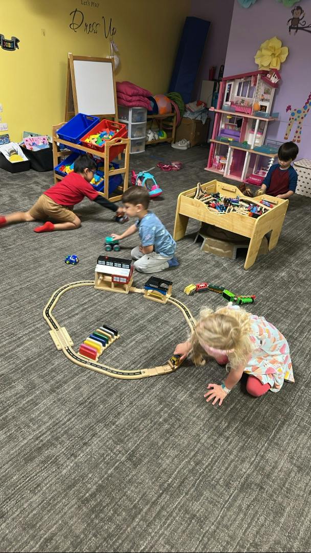 Children playing with train sets and toys in a playroom