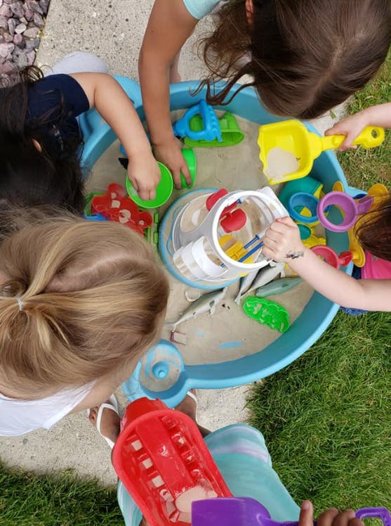 Children playing in a sand and water table with toys