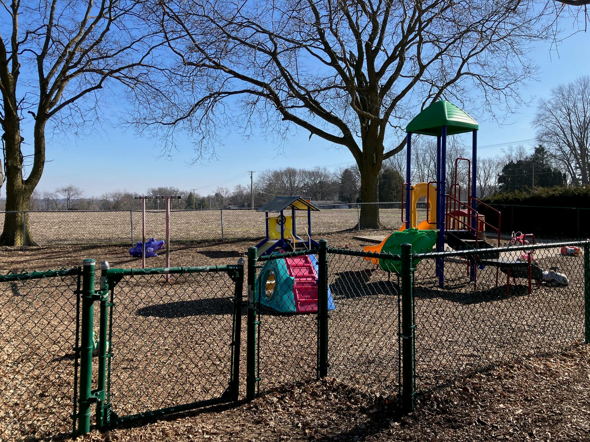 Playground with swings and slides behind a chain link fence