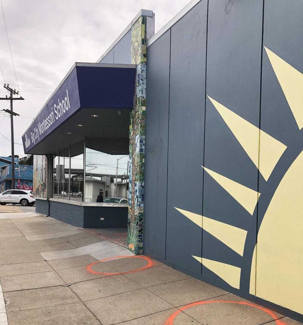 Building with "Montessori School" sign and sun mural on the side