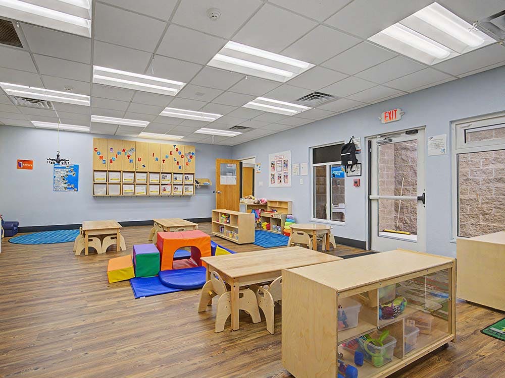 Empty classroom with small wooden tables and colorful soft play shapes