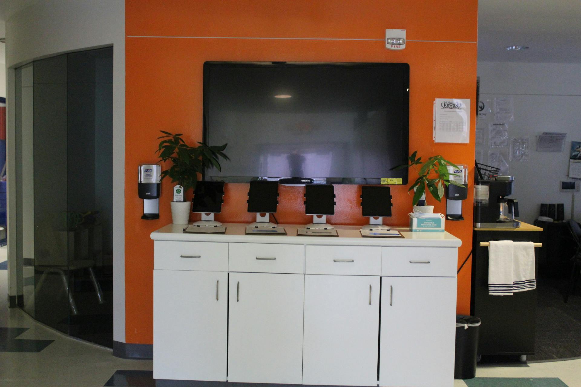 Four computer monitors on a white cabinet below a large screen on an orange wall