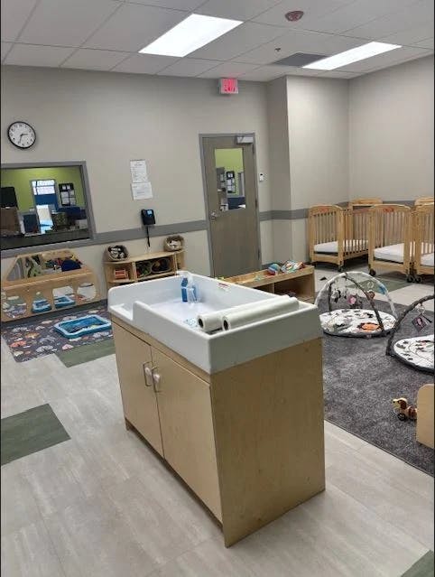 Changing station in a room with cribs and play mats