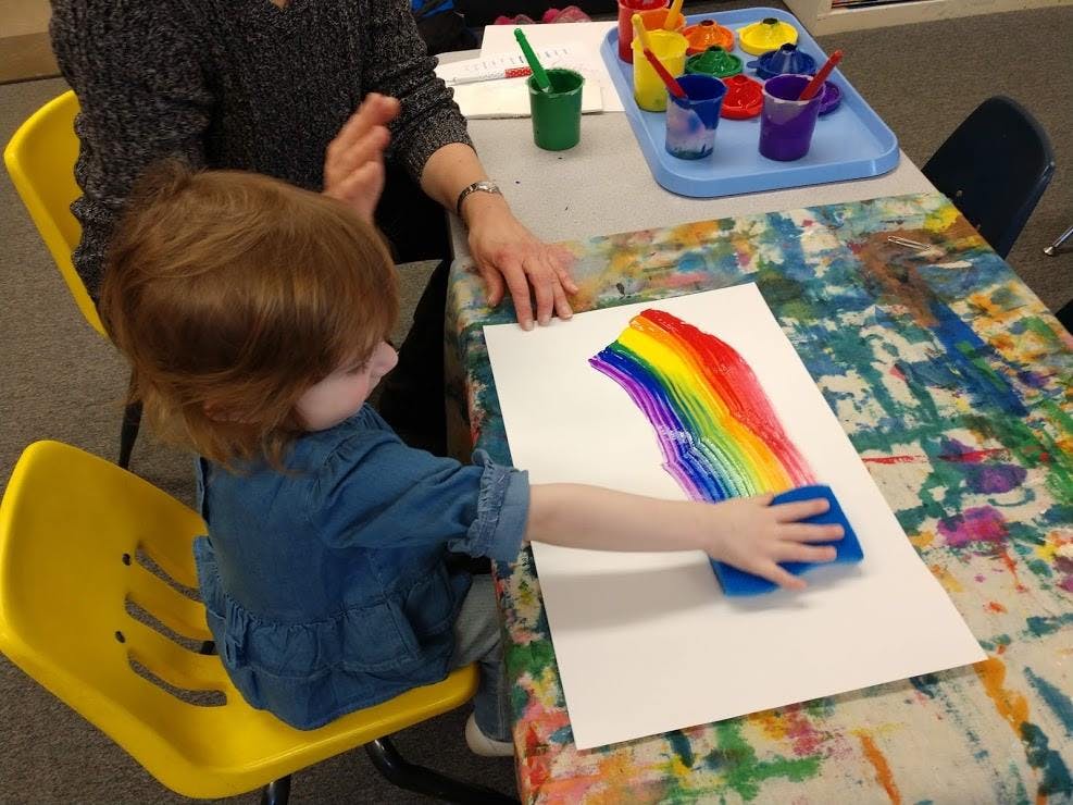 Child painting a rainbow with a sponge